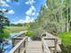 Scenic view of a wooden dock on a tranquil lake with lily pads and lush green trees under a blue sky at 1014 Sylvia Ln, Tampa, FL 33613