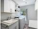 Bright laundry room featuring modern white cabinetry, sink, laundry machines, neutral walls and a window at 1014 Sylvia Ln, Tampa, FL 33613