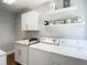 Bright laundry room featuring modern white cabinetry, sink, laundry machines, neutral walls and decorative shelving at 1014 Sylvia Ln, Tampa, FL 33613