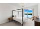 Bright bedroom featuring a four poster bed and scenic water views from a large window at 1020 Sunset Point Rd # 410, Clearwater, FL 33756