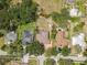 An aerial view of a backyard with a screened-in pool, mature trees, and surrounding landscape at 10306 Shalimar Wood Dr, Thonotosassa, FL 33592