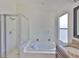 Bathroom featuring a soaking tub, stand-up shower, white tiles and a window providing natural light at 11726 S Stone Ln, Riverview, FL 33569