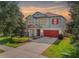 Charming two-story home boasts a well-manicured lawn, red garage door and shutters, and an inviting sunset at 11802 Twilight Darner Pl, Riverview, FL 33569