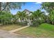 Charming home with mature tropical landscaping, lush green lawn and a welcoming walkway leading to the front porch at 1211 14Th N St, St Petersburg, FL 33705