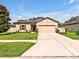 Beautiful one-story home featuring a well-manicured lawn, neutral tan paint, and a two-car garage at 12428 Chaya Ct, Spring Hill, FL 34610