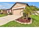 Charming one-story home with a well-manicured lawn, neutral tan paint, and a two-car garage at 12428 Chaya Ct, Spring Hill, FL 34610