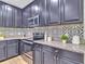 Stylish kitchen featuring sleek, dark cabinetry, granite countertops, stainless steel appliances, and a decorative tile backsplash at 12428 Chaya Ct, Spring Hill, FL 34610