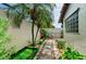 Well-manicured backyard featuring a stone walkway, lush landscaping, a black metal gate, and privacy wall at 13544 Avista Dr, Tampa, FL 33624