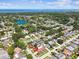 Expansive aerial view of neighborhood homes near a lake, with the highlighted property featuring lush landscaping and brick accents at 1436 Santa Clara Dr, Dunedin, FL 34698