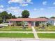Charming single-story home featuring a well-maintained lawn and mature landscaping under a sunny sky at 1436 Santa Clara Dr, Dunedin, FL 34698