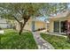 Quaint yellow home with a walkway, lush landscaping, and a charming blue front door at 15005 Roundup Dr, Tampa, FL 33624