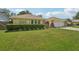 Charming yellow home with a well-manicured lawn and beautiful landscaping at 15005 Roundup Dr, Tampa, FL 33624