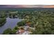 A birds-eye view of the home on a wooded lot, backing onto a lake with lush trees at 16112 N 15Th St, Lutz, FL 33549