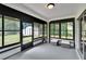 View of a sunroom with black trimmed windows, a view of the yard, and small white ottomans at 16112 N 15Th St, Lutz, FL 33549