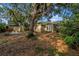 Extensive backyard, showcasing mature trees, ground cover, and a wooden deck with outdoor seating at 1753 San Mateo Dr, Dunedin, FL 34698