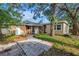 Charming home with a landscaped yard, mature trees, and a concrete walkway at 1753 San Mateo Dr, Dunedin, FL 34698