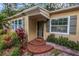 A close up view of the porch with red tile steps and mature landscaping surrounding the entry at 1753 San Mateo Dr, Dunedin, FL 34698