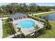 Community pool with a covered lounge area surrounded by lush tropical landscaping and a scenic pond at 17881 Star Ruby Pl, Nokomis, FL 34275