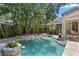 Backyard pool featuring stone trim, integrated waterfall feature, outdoor bar, and mature landscaping at 1805 W Jetton Ave, Tampa, FL 33606