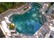 Aerial shot of an geometric shaped pool with light blue water surrounded by stone and tropical landscaping at 1805 W Jetton Ave, Tampa, FL 33606