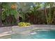 Water feature spills into pool surrounded by lush landscaping with privacy fence in the background at 1805 W Jetton Ave, Tampa, FL 33606