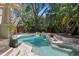 A private backyard pool features stone trim, tile accents, and mature landscaping at 1805 W Jetton Ave, Tampa, FL 33606