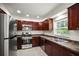 Well-lit kitchen featuring stainless steel appliances, dark wood cabinets, and tile flooring at 1880 Fuller Dr, Clearwater, FL 33755