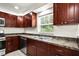 Kitchen with stainless steel appliances, dark wooden cabinets, and a window with natural light at 1880 Fuller Dr, Clearwater, FL 33755