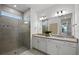Bathroom featuring a tiled shower with glass door, double vanity with white cabinets, and large mirror at 18913 Indian Rock Pl, Lakewood Ranch, FL 34211
