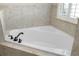 Close-up of a bright white bathtub with tiled surround and bronze fixtures at 203 Montara Dr, Seffner, FL 33584