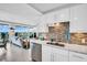 Modern kitchen with white cabinets, stainless steel appliances, and a stylish backsplash, seamlessly connected to the living area at 223 Island Way # 7F, Clearwater Beach, FL 33767