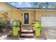 Charming home entrance with a lovely door, wooden deck, potted plants and a two-car garage at 2503 Victarra Cir, Lutz, FL 33559