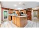 Kitchen featuring wooden cabinetry, tile backsplash, black appliances, an island and white tile floors at 2911 Pemberton Creek Dr, Seffner, FL 33584