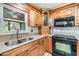 Kitchen featuring wooden cabinetry, tile backsplash, black appliances, and a stainless steel sink at 2911 Pemberton Creek Dr, Seffner, FL 33584