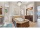 Elegant bathroom with a large soaking tub, travertine tile, and a decorative chandelier at 301 Bayview Ne Dr, St Petersburg, FL 33704