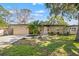 Charming single-story home with manicured lawn, complemented by lush landscaping and mature trees at 310 55Th S Ave, St Petersburg, FL 33705