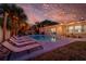 Inviting backyard with a sparkling pool, lounge chairs, string lights, and lush landscaping at 3485 Floral Dr, Largo, FL 33771