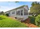 Back of home featuring a sunroom, steps, green grass and mulch at 37420 Teaberry Loop, Zephyrhills, FL 33542