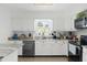 Modern kitchen with sleek black appliances, granite countertops, white cabinetry and a garden window over the sink at 37420 Teaberry Loop, Zephyrhills, FL 33542