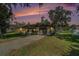 Charming single-story home featuring a garage, driveway, and lush greenery, set against a colorful sunset at 4221 Burrows Rd, Zephyrhills, FL 33542