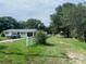 A view of a single-story home with a vehicle parked in the driveway, with a path that leads to an outbuilding at 4316 E Knights Griffin Rd, Plant City, FL 33565