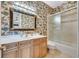Bathroom featuring animal print wallpaper, framed mirror, and shower-tub combination at 4641 John Moore Rd, Brandon, FL 33511