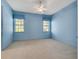 Blue bedroom with neutral carpet, two windows, and a ceiling fan for comfortable living at 4641 John Moore Rd, Brandon, FL 33511
