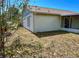 Side view of home with a brown roof, tan exterior, and a compact grassy area with trees and vegetation at 502 Chilt Dr, Brandon, FL 33510