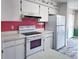 Functional kitchen featuring white appliances, white cabinets, and floral wallpaper accents at 502 Chilt Dr, Brandon, FL 33510