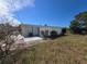 Exterior view shows the side of the house with an AC unit, overgrown yard, and blue door at 5031 Billings Dr, Holiday, FL 34690