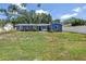 View of the home's fenced backyard with blue home exterior and outdoor patio area with table and chairs at 5947 46Th N Ave, Kenneth City, FL 33709