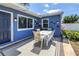 Backyard patio area featuring a table with chairs, plants, and the blue house with a white trimmed window at 5947 46Th N Ave, Kenneth City, FL 33709