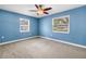 Light blue bedroom with neutral carpet, ceiling fan and natural light from two windows at 5947 46Th N Ave, Kenneth City, FL 33709