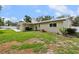 Wide backyard featuring a covered patio, green grass, and partial sunshine with a metal roof at 708 Westwood Cir, Brandon, FL 33511